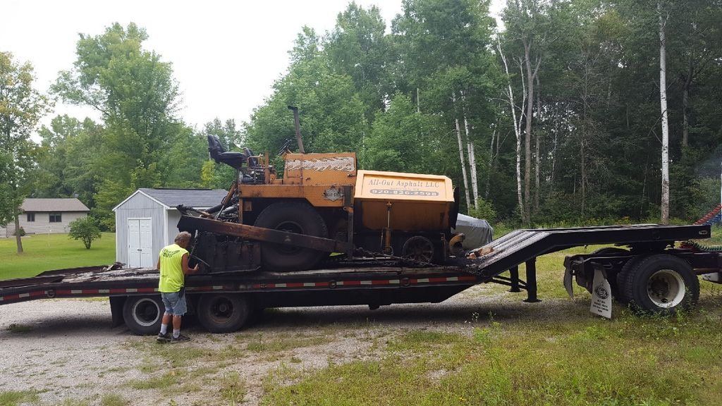 A man is standing next to a trailer with a machine on it.