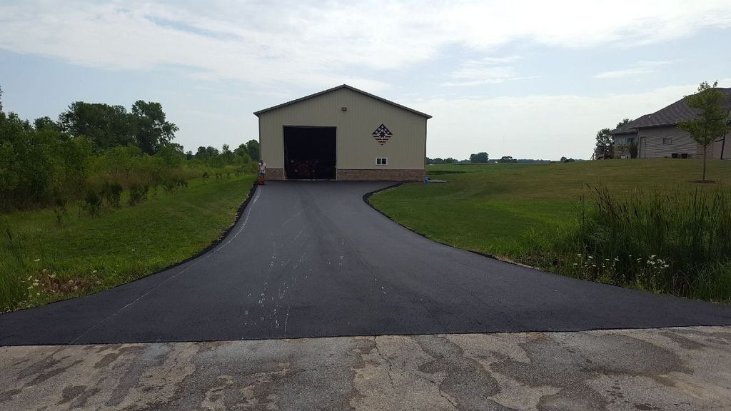 A driveway leading to a garage in the middle of a grassy field.
