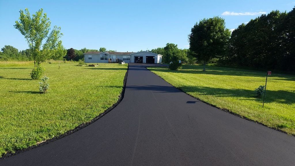 A driveway leading to a house surrounded by grass and trees