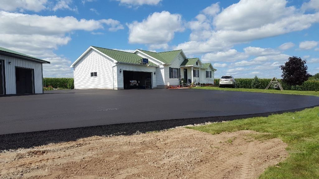 A white house with a green roof and a car parked in front of it.