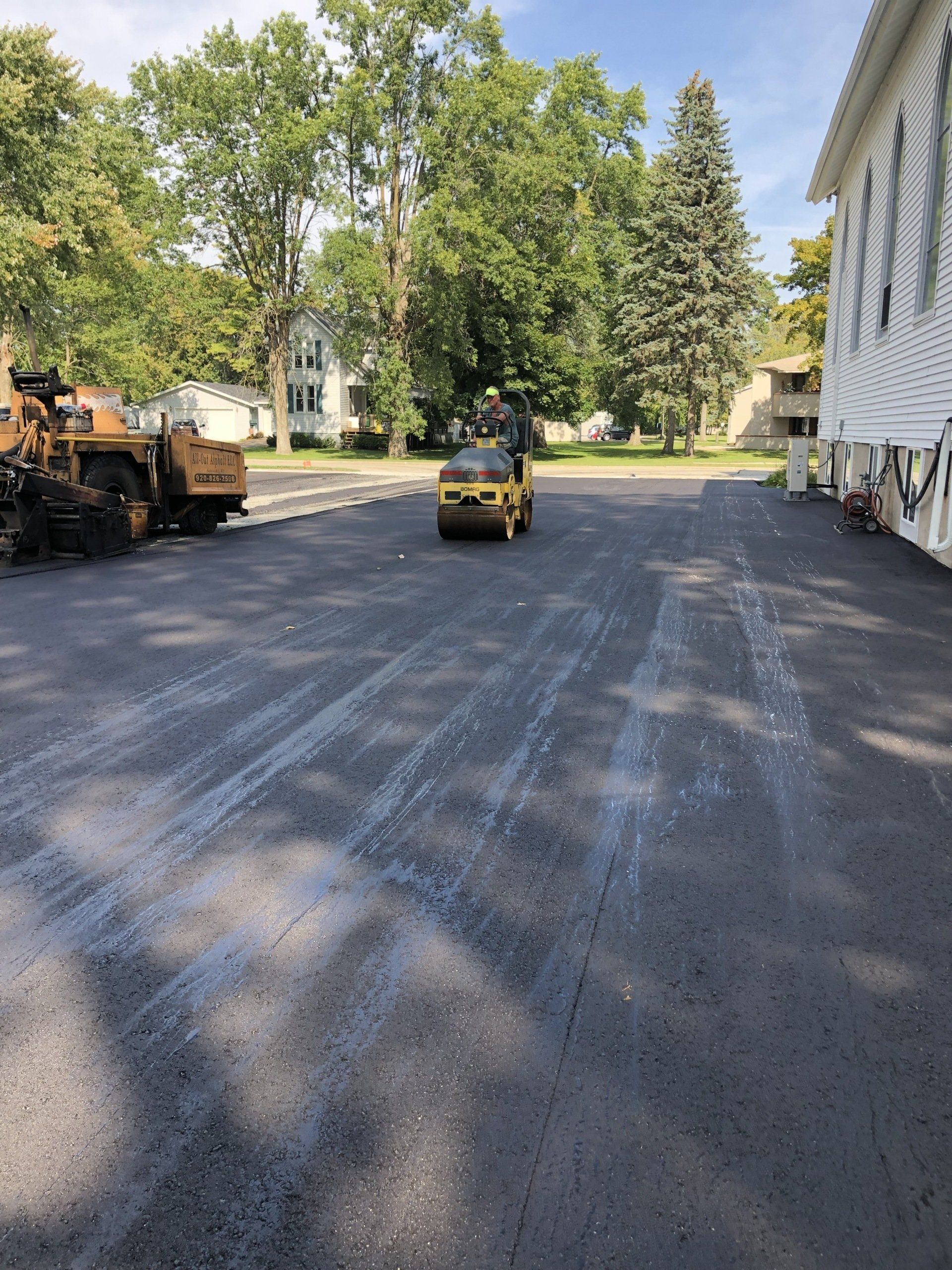 A yellow car is driving down a road next to a building