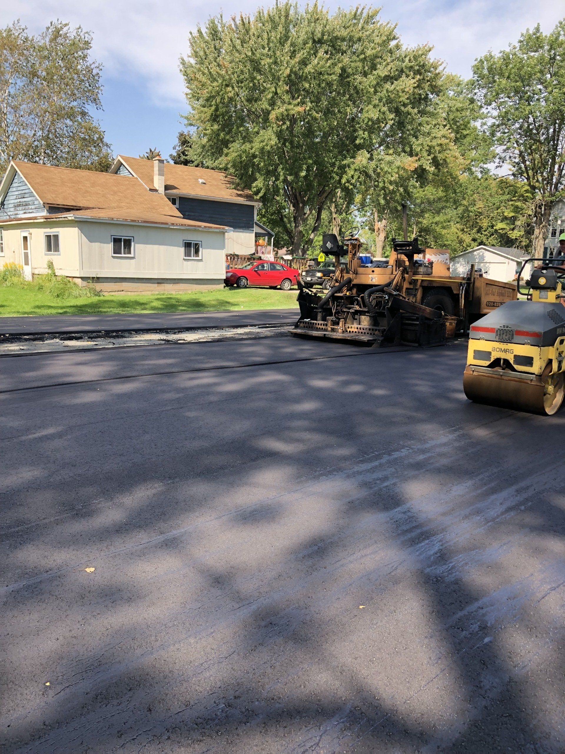 A row of construction vehicles are working on a road.