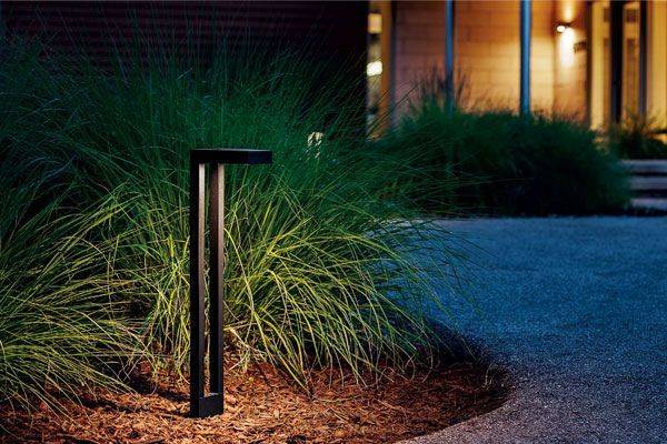 A pole with a light on it is in the middle of a garden.