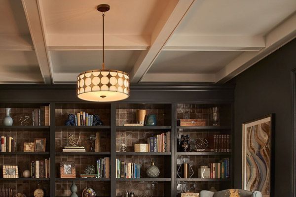 A living room with a lot of bookshelves and a lamp hanging from the ceiling.