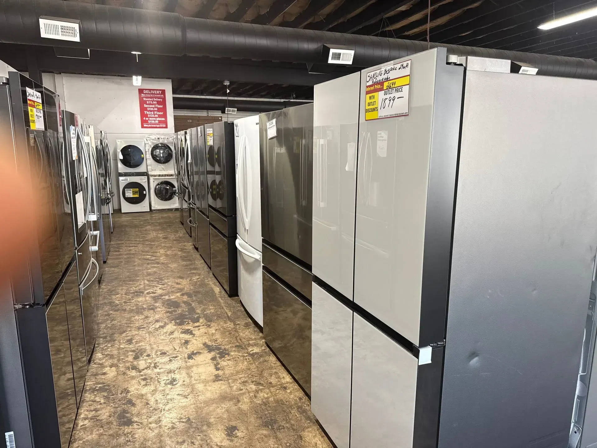 Refrigerators and washing machines displayed in a showroom.