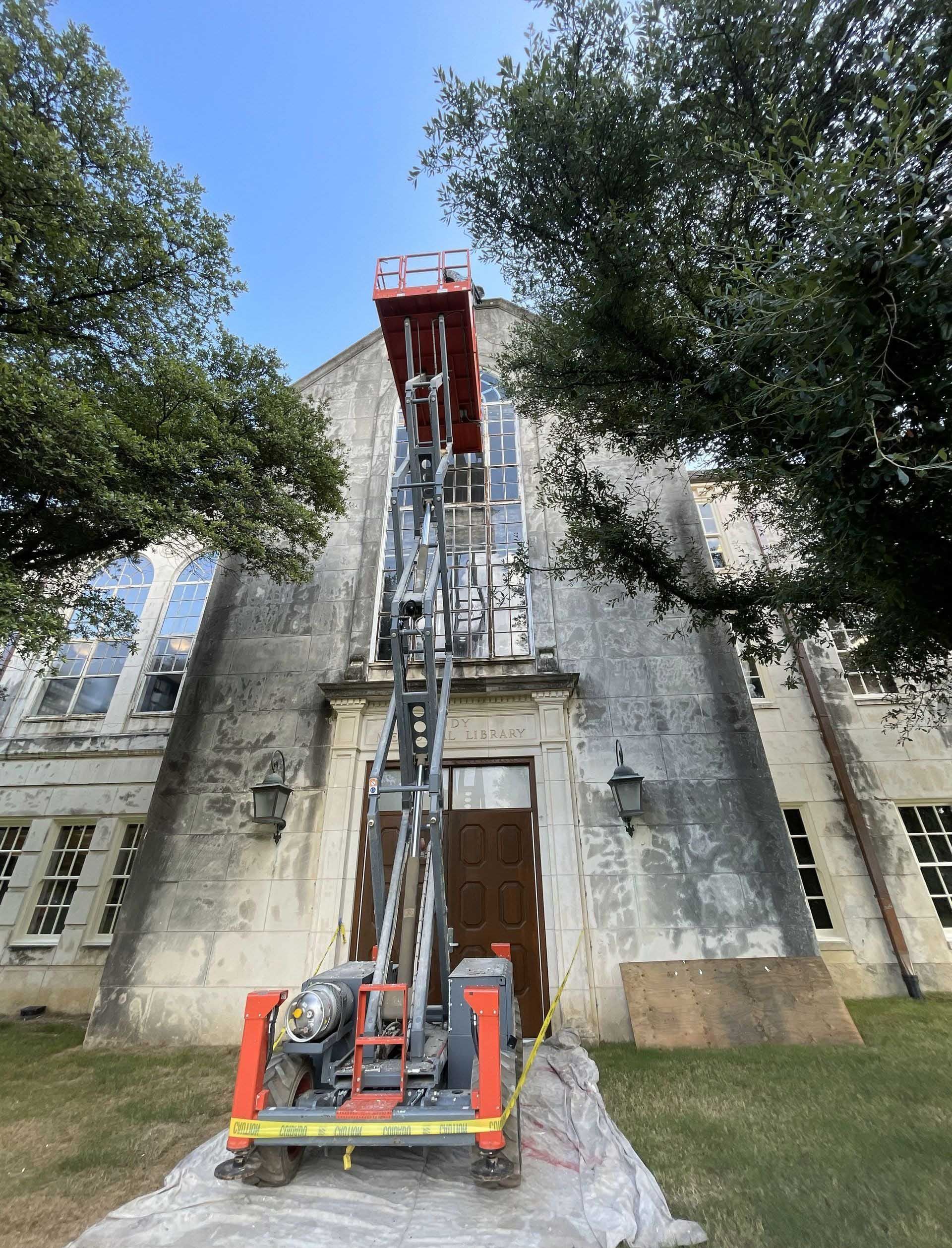Lift extending upward in front of a stone building with windows and a doorway.