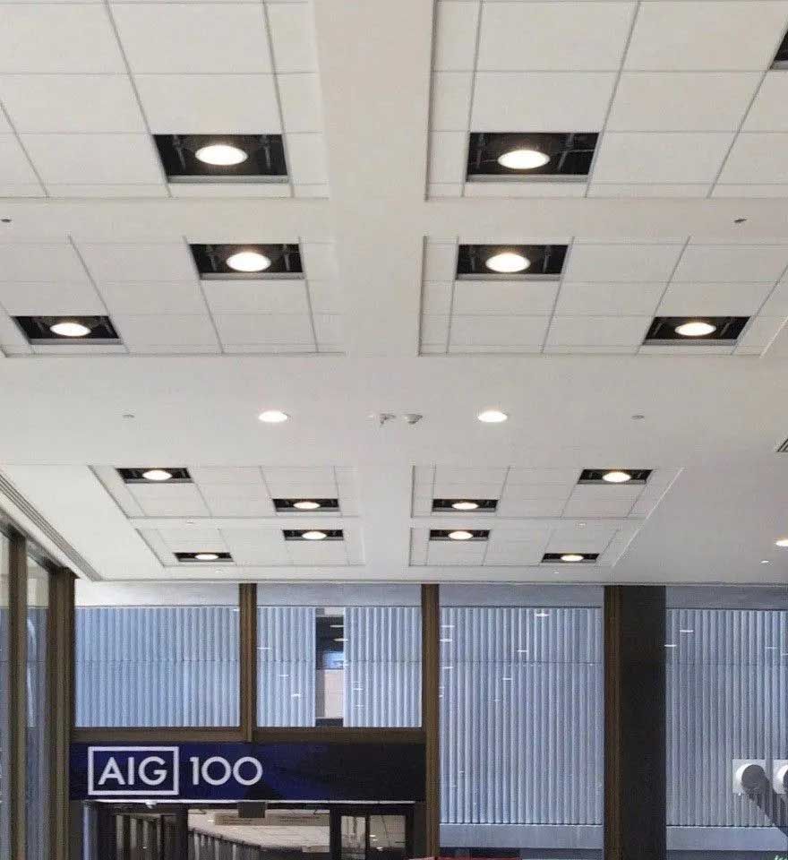 White ceiling with recessed square lights; AIG 100 sign visible.