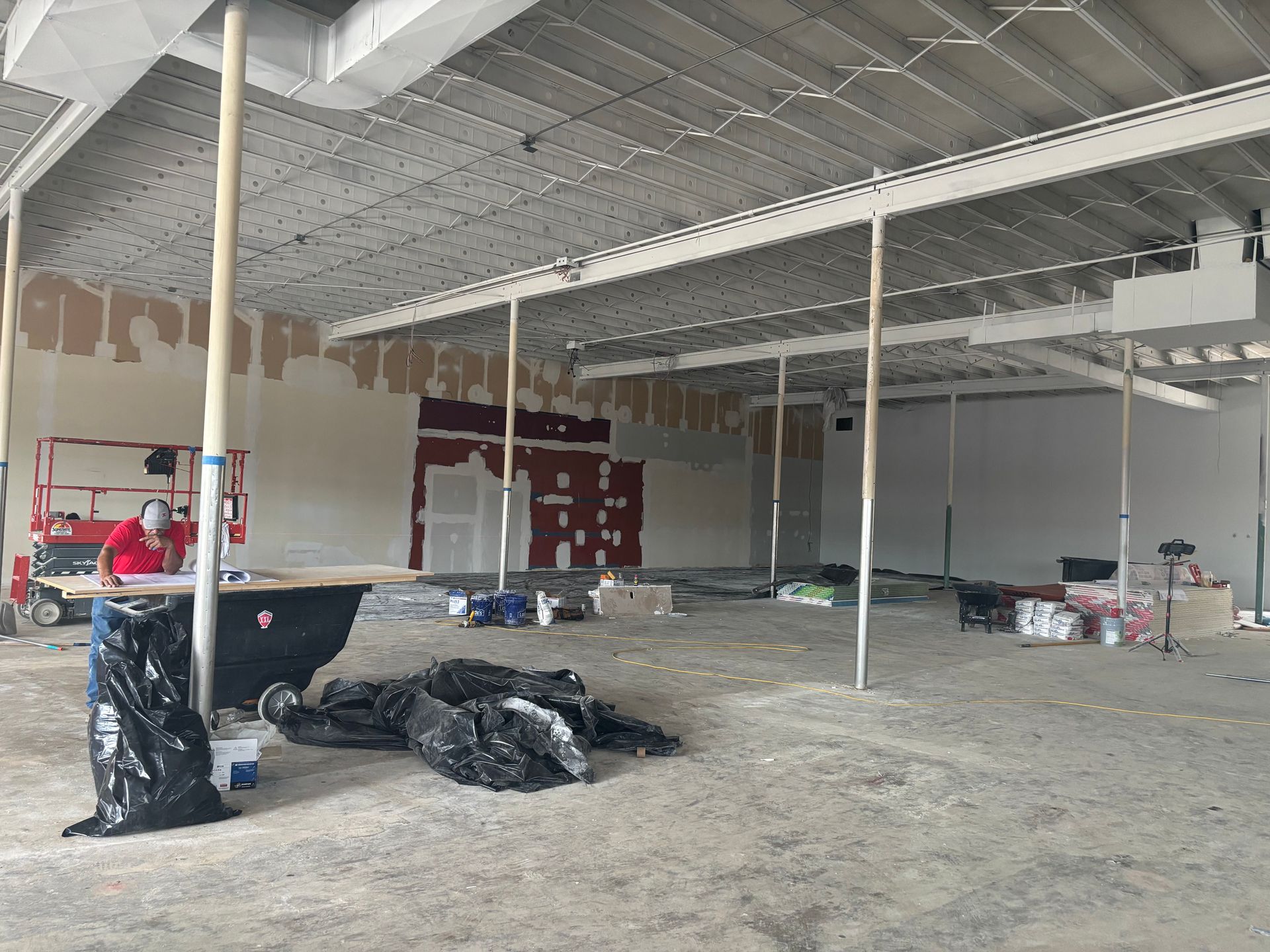 Interior of unfinished commercial space under construction; drywall, supports, construction materials.