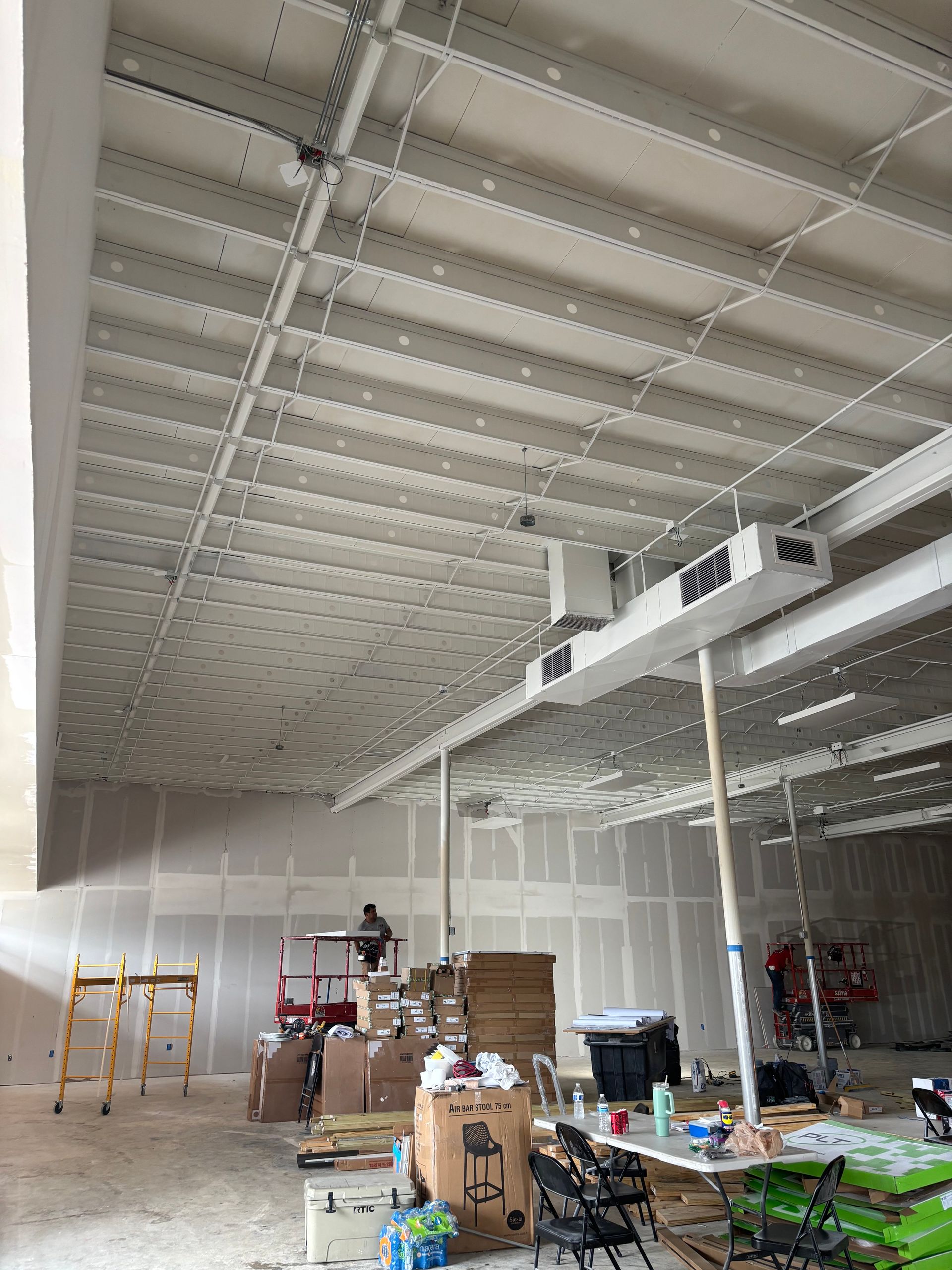 Interior view of a building under construction. The ceiling is white, and the walls are unfinished drywall.