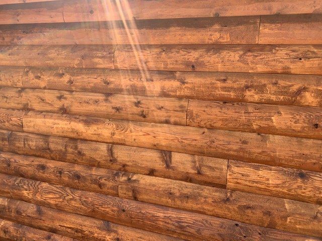 A close up of a log wall with the sun shining through it.