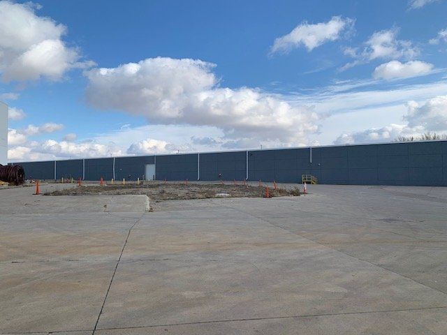 A large building in the background has many clouds in the sky.