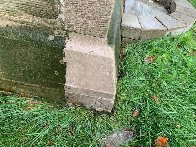 A brick wall is sitting on top of a lush green field.