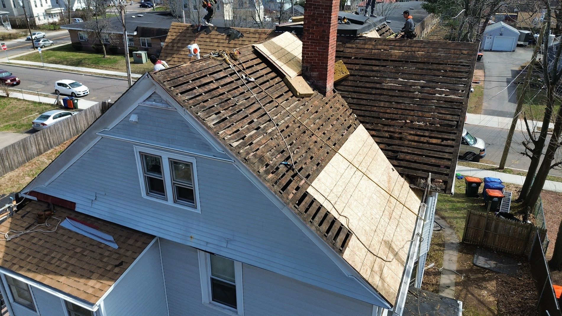 Aerial view of a house with a damaged, partially missing roof shingles and exposed sections.