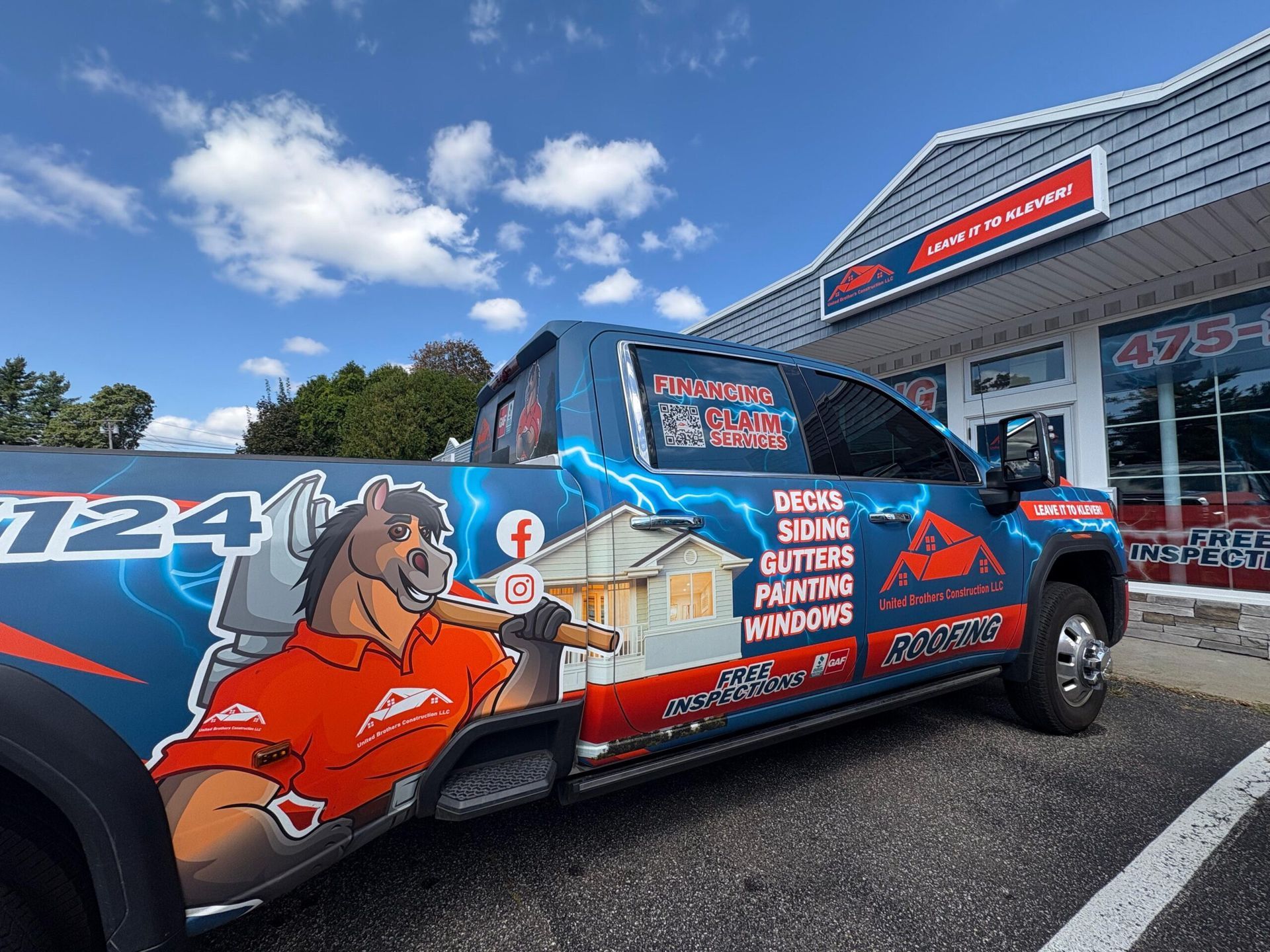 Wrap-covered pickup truck parked outside a storefront under a blue sky
