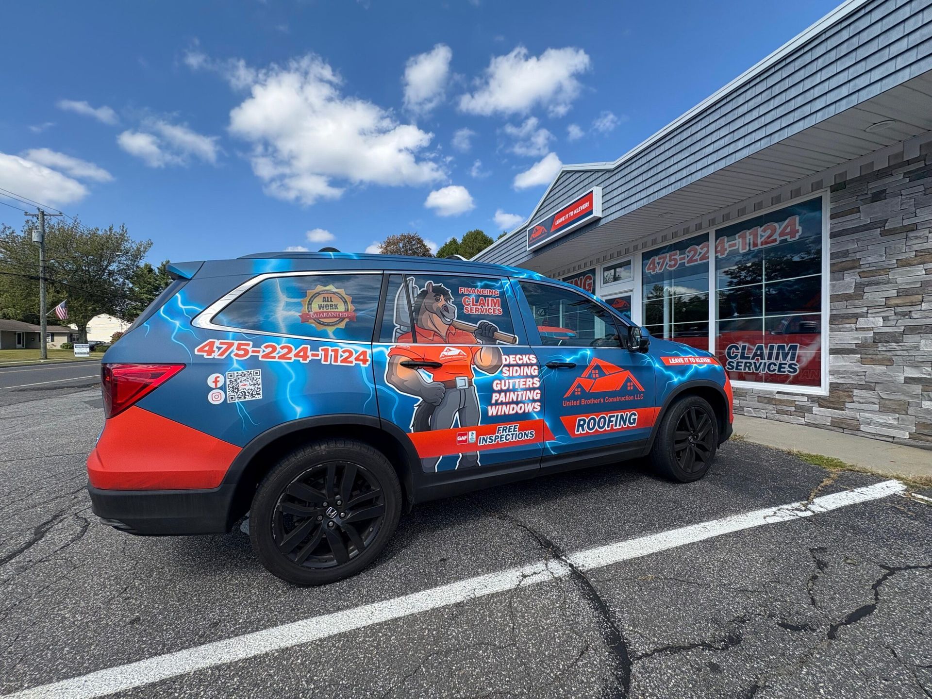 Blue and red wrapped SUV parked outside a storefront on a sunny day