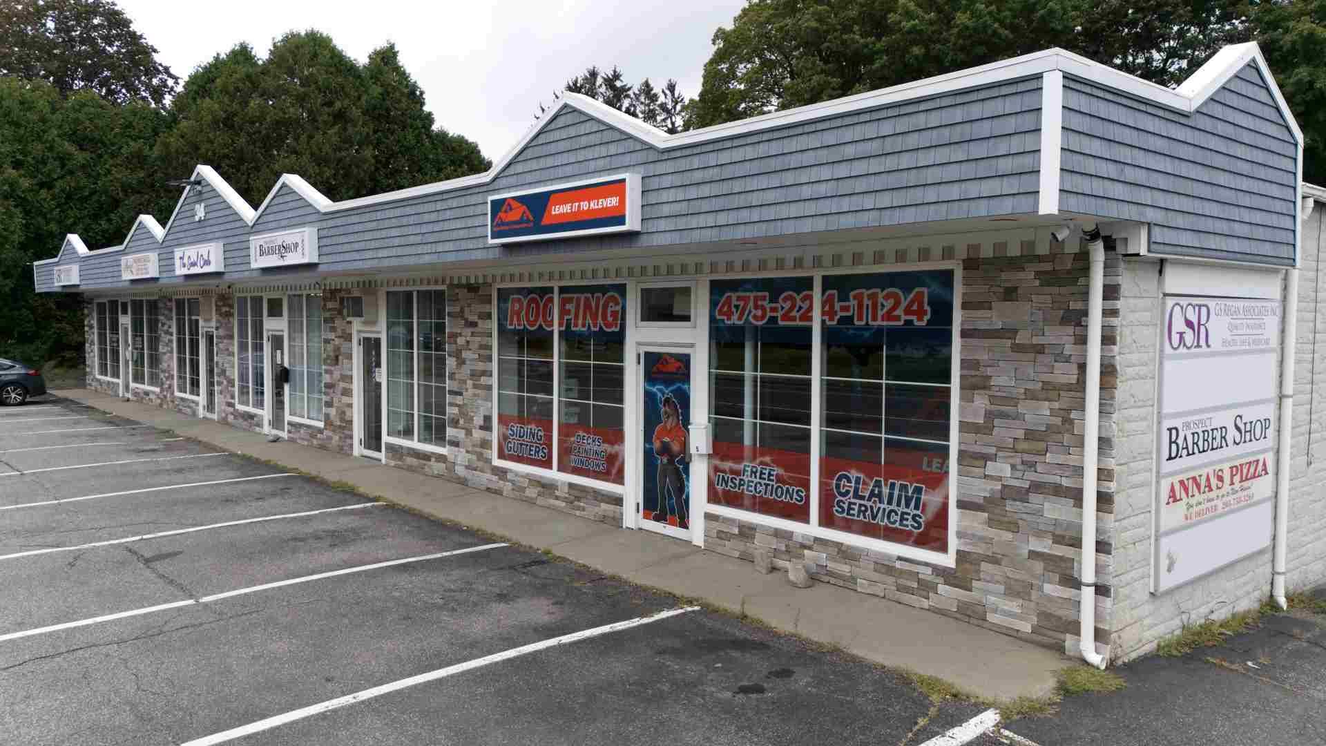 Strip mall storefront with stone facade, large windows, and empty parking lot