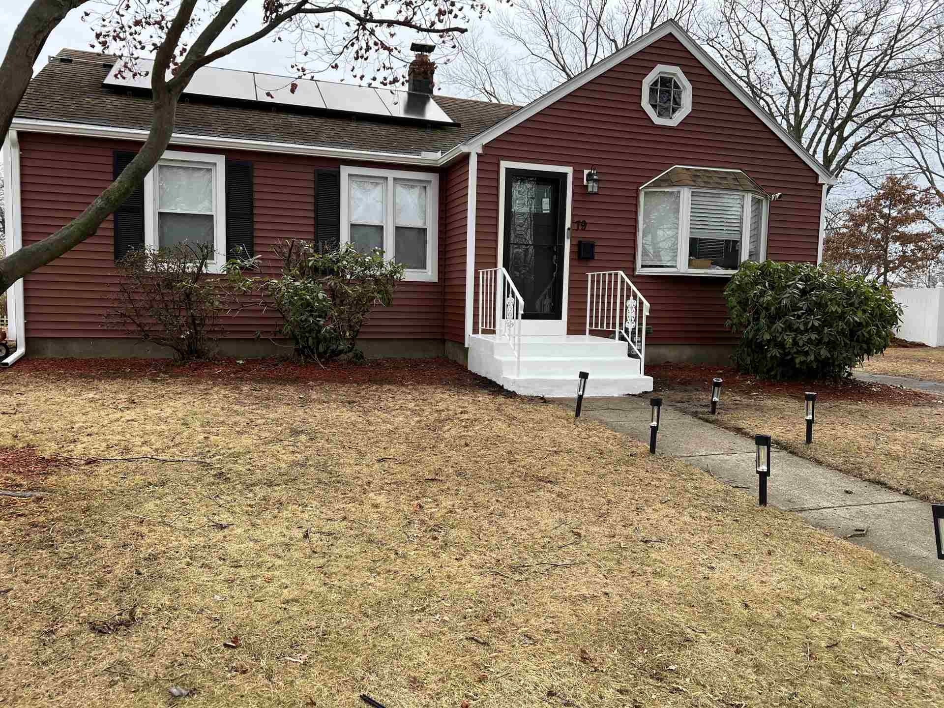 Small red house with white trim and front steps, viewed from a wintery lawn.