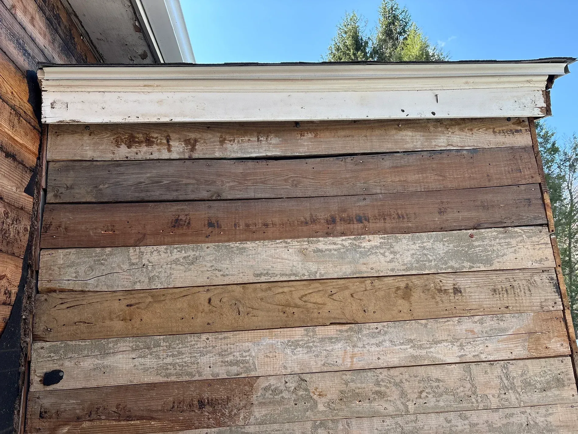 Weathered wooden beehive box outdoors with a white top and horizontal plank sides