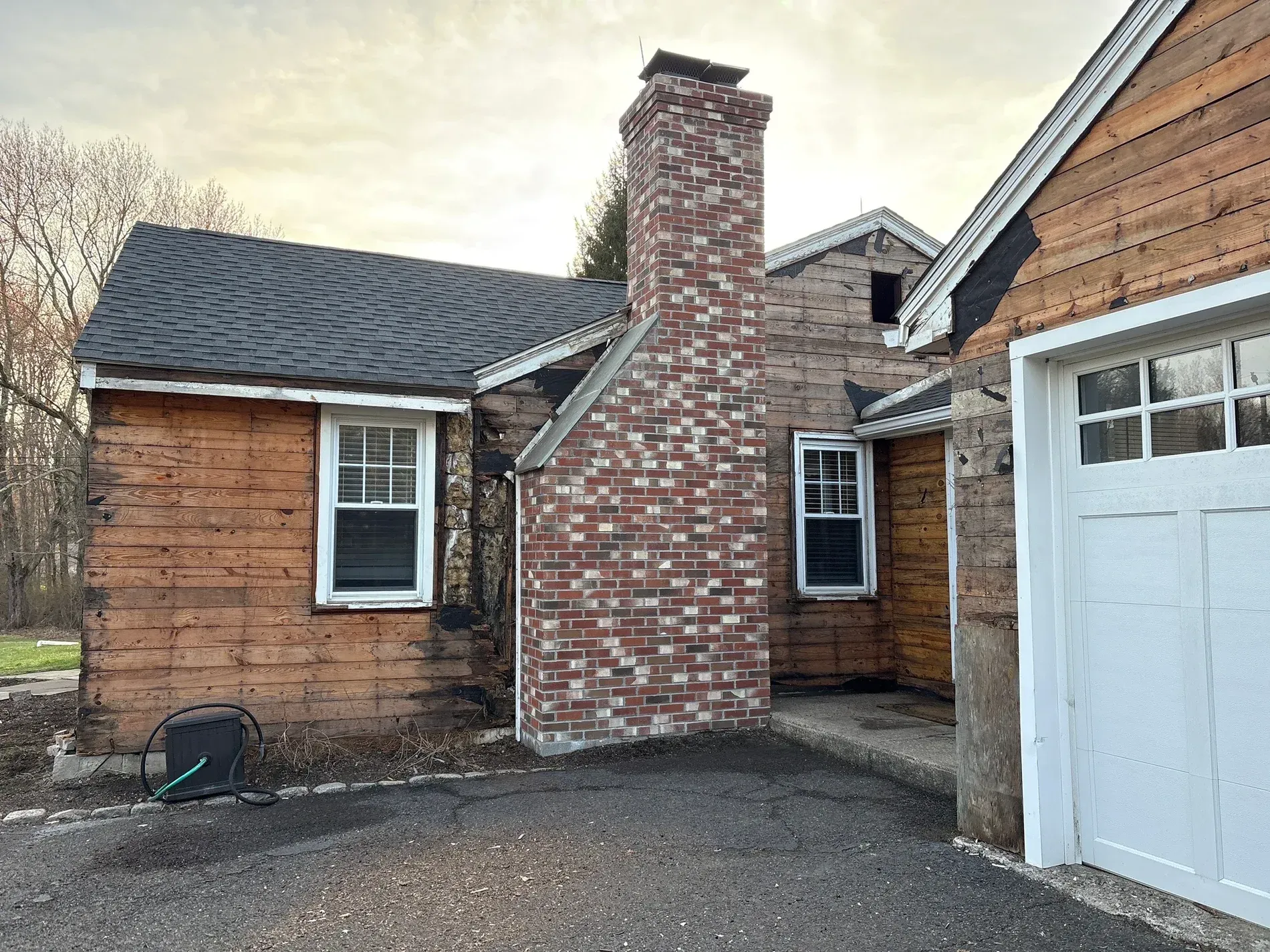 Brick and wood exterior of a house with a central chimney and white garage door