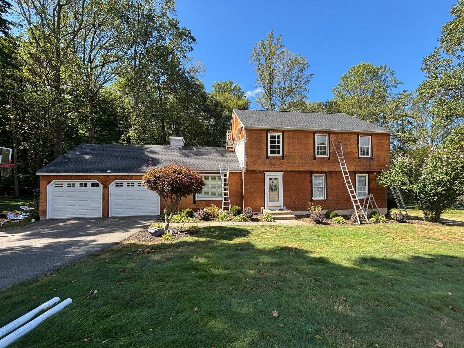 Two-story brick house with attached two-car garage, white-trim windows, and a front lawn on a sunny day