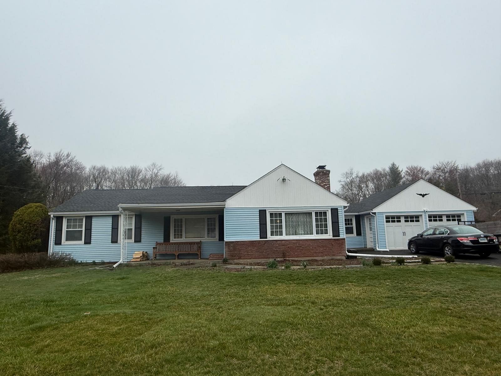 Single-story blue house with brick trim and detached garage on a cloudy day