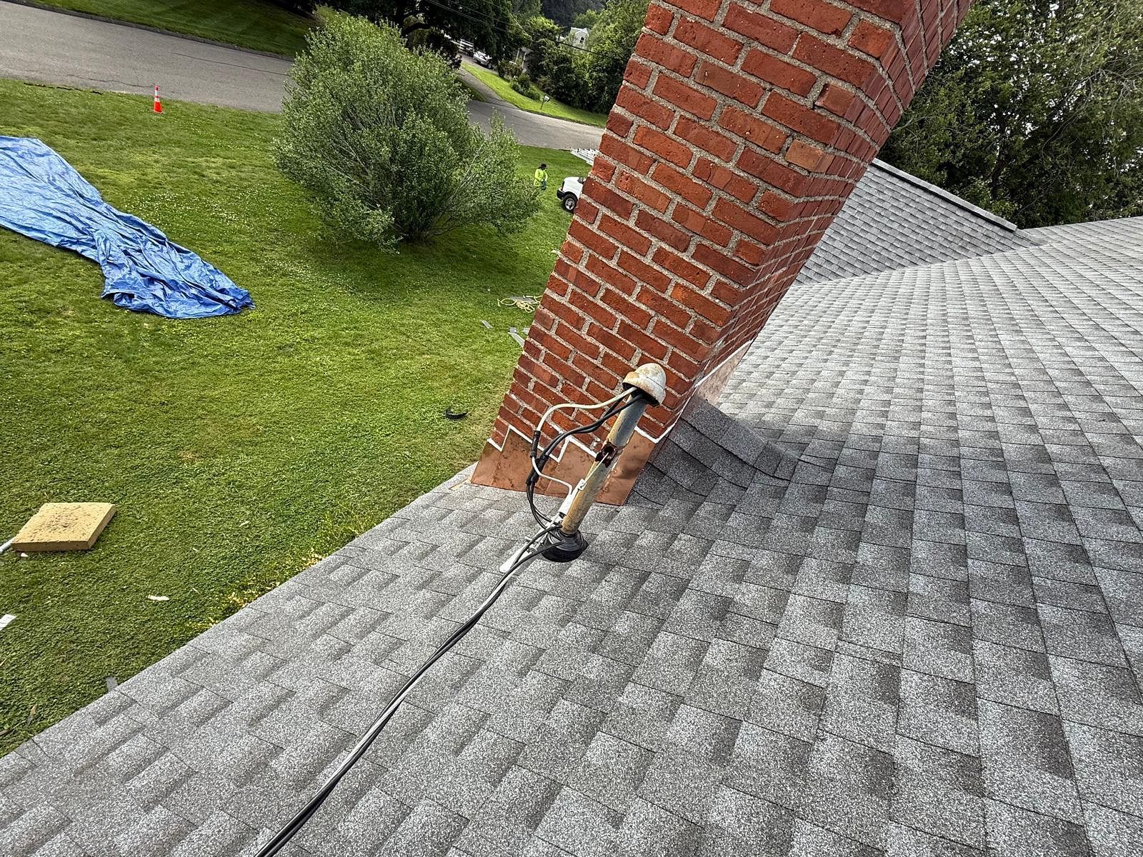 Roof with damaged shingles and a brick chimney on a house exterior