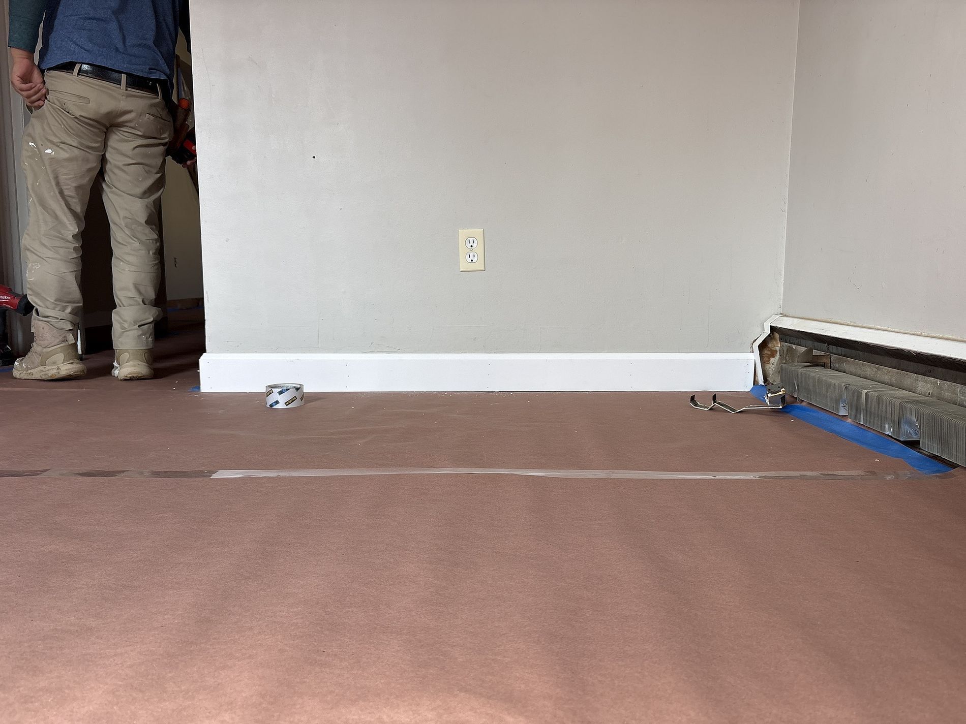 Partially finished room with bare walls, carpet, and a person standing near the left wall