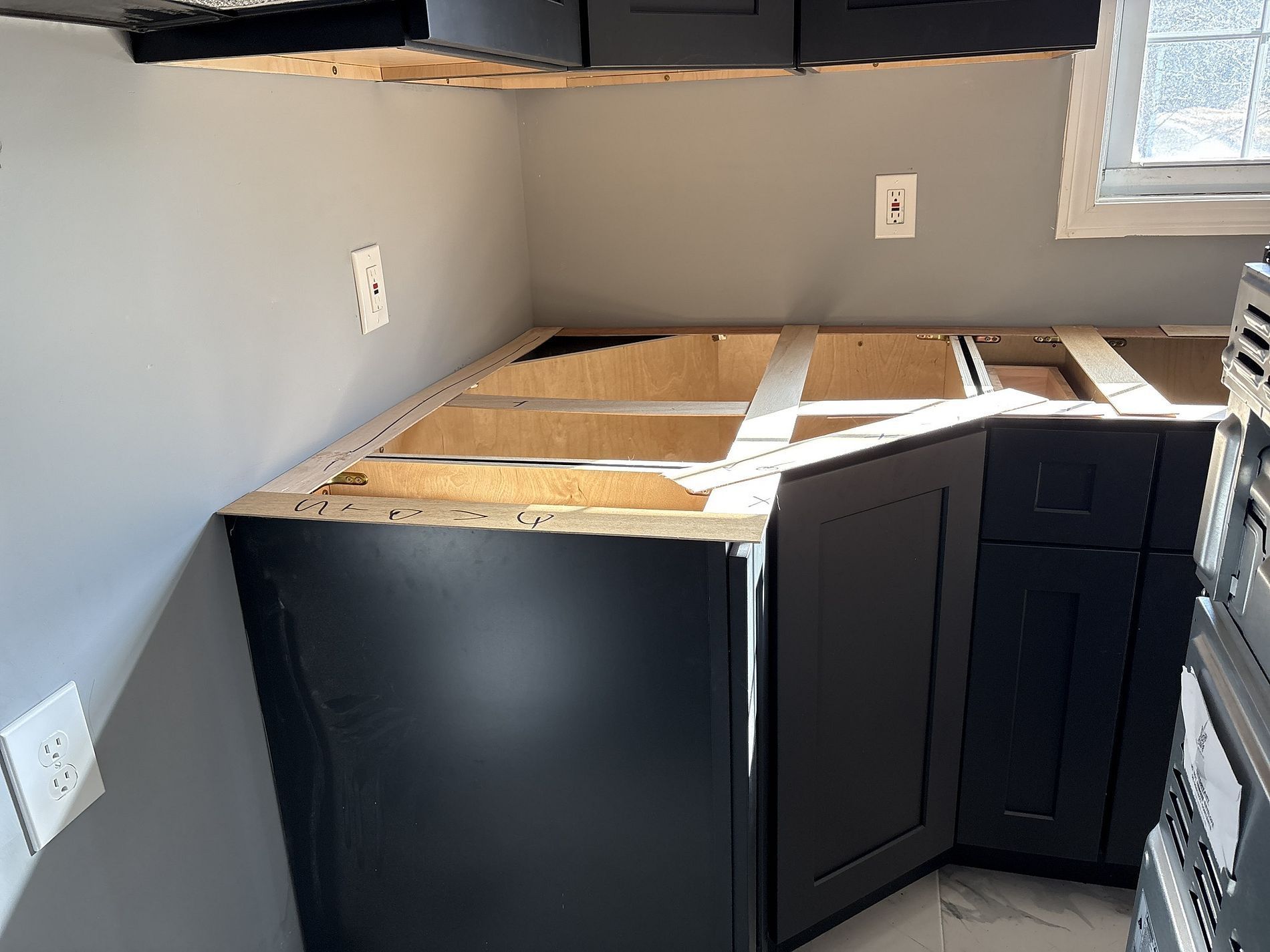 Partially installed kitchen cabinets with exposed wood countertop framing in a room under renovation