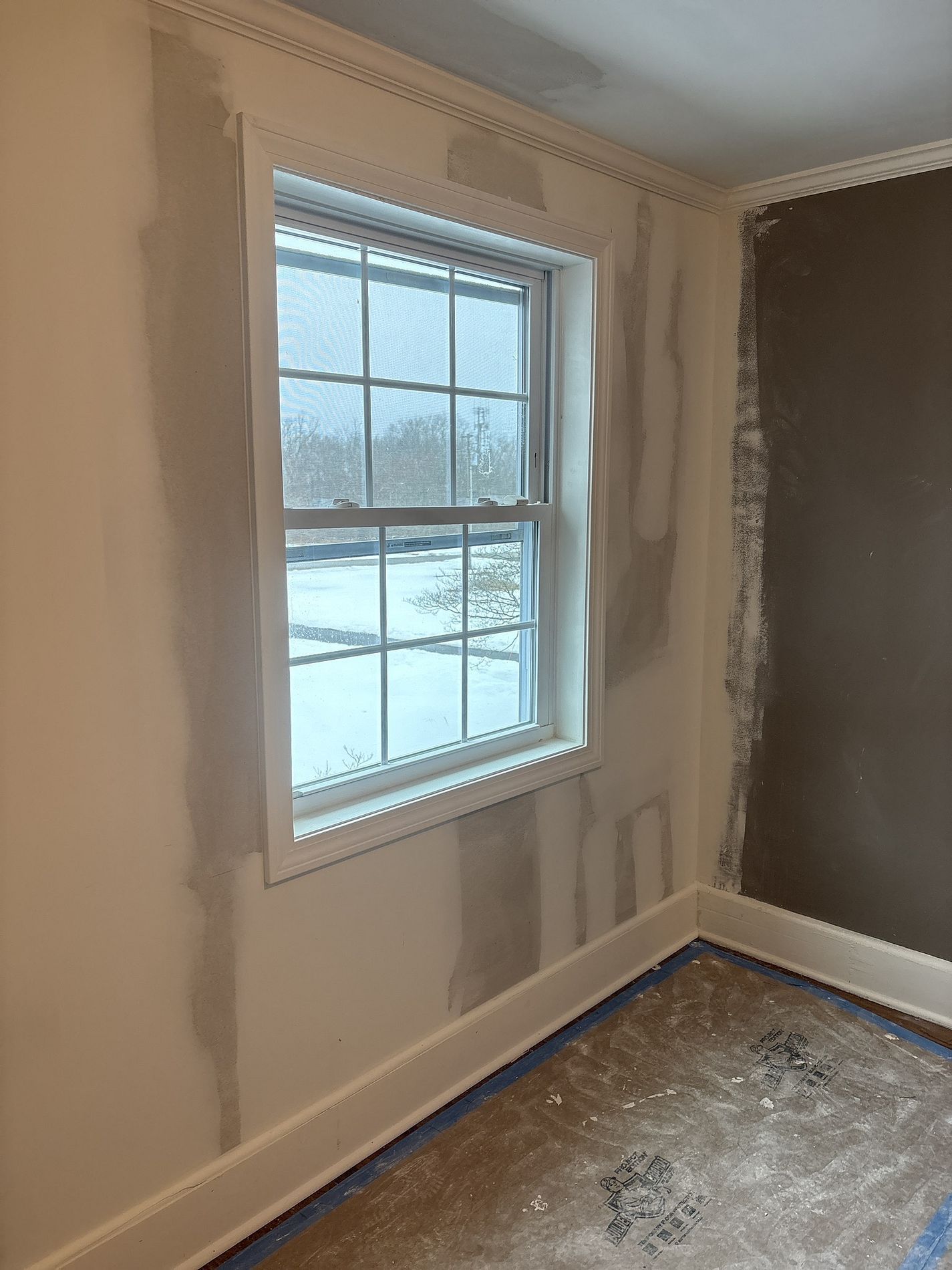 Freshly painted room with a window, white trim, and unfinished floor near the baseboards
