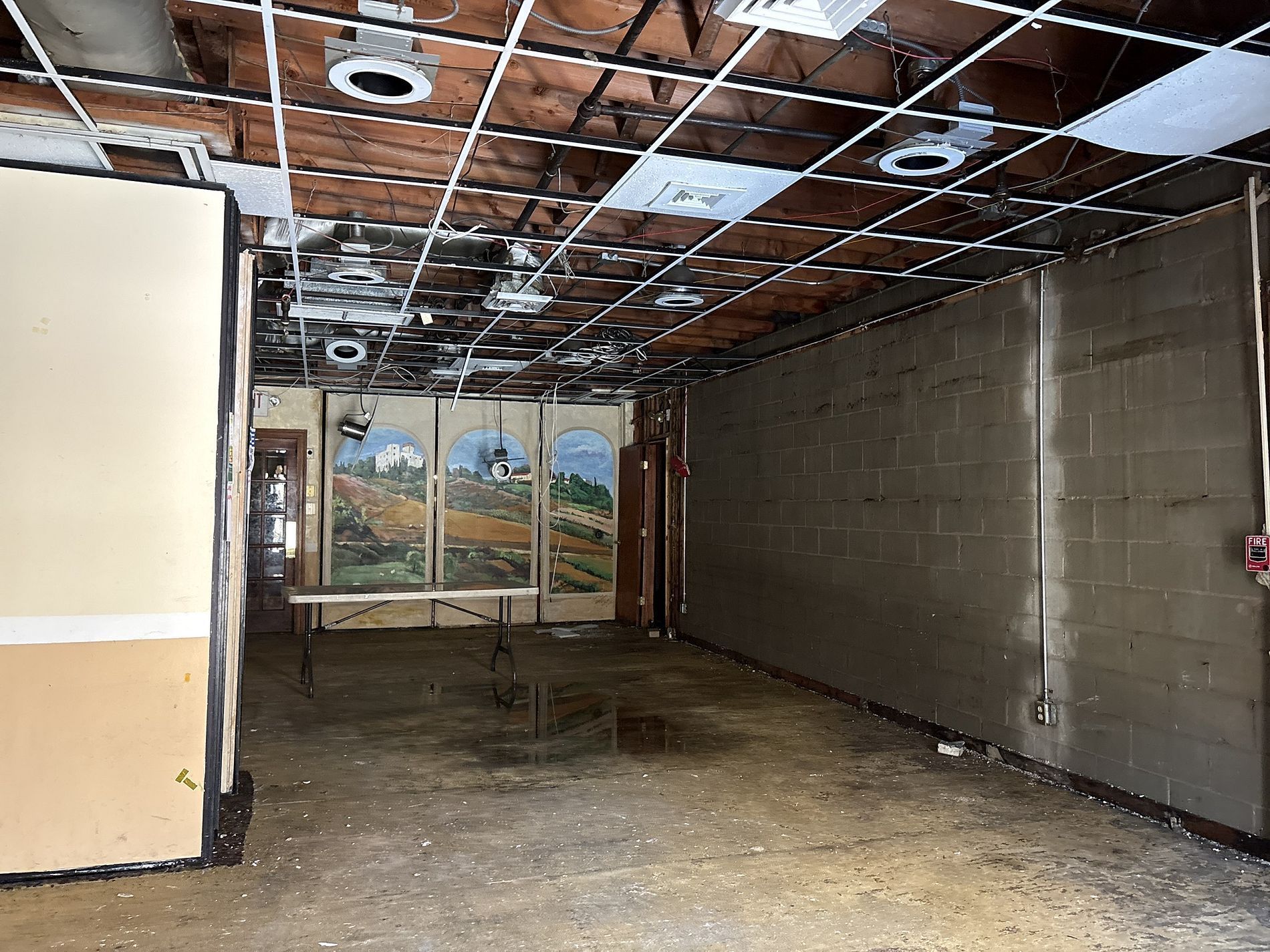 Empty unfinished room with exposed ceiling, cinderblock walls, and muddy floor.