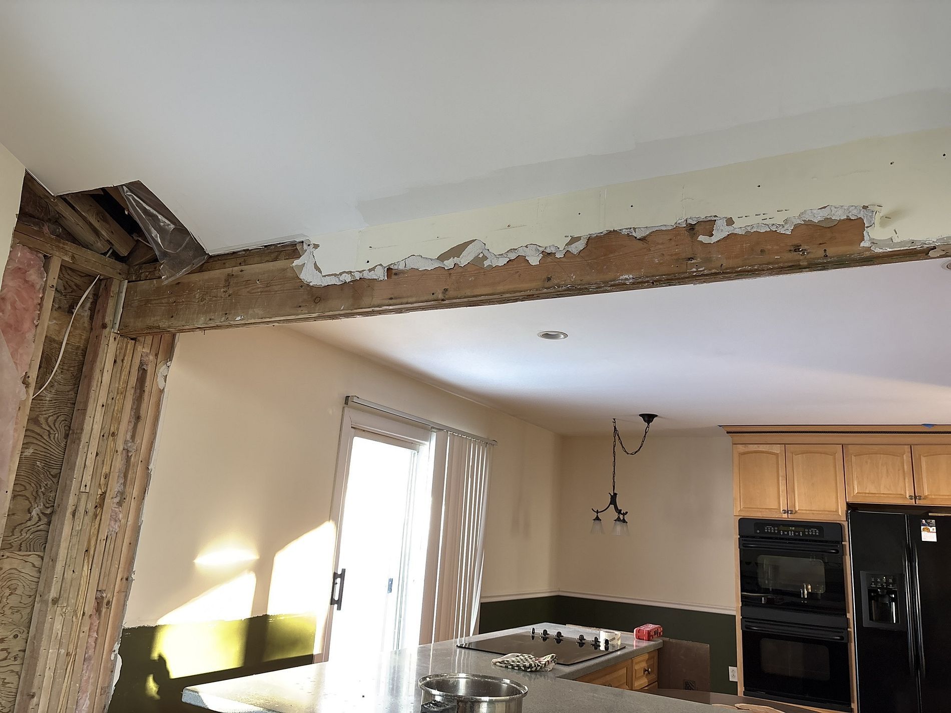 Partially demolished kitchen with exposed wood beam and damaged wall above the doorway