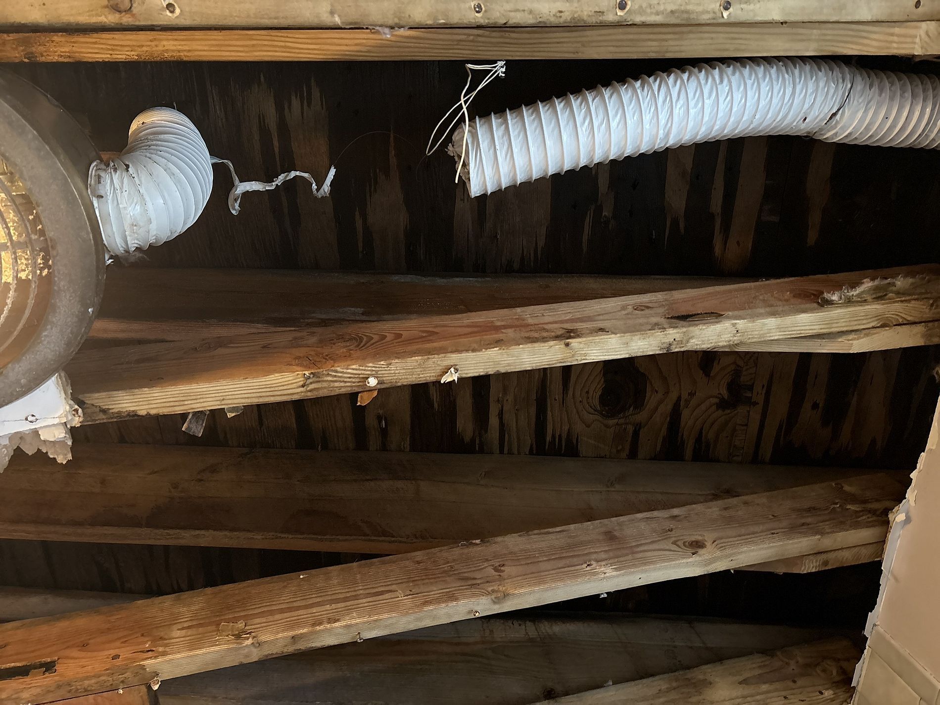 Exposed wooden ceiling joists with white insulated ducting and a visible light fixture