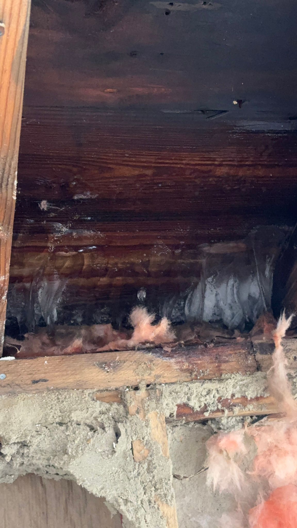 Charred wooden interior with blackened walls, ash, and smoke stains near the floor and opening