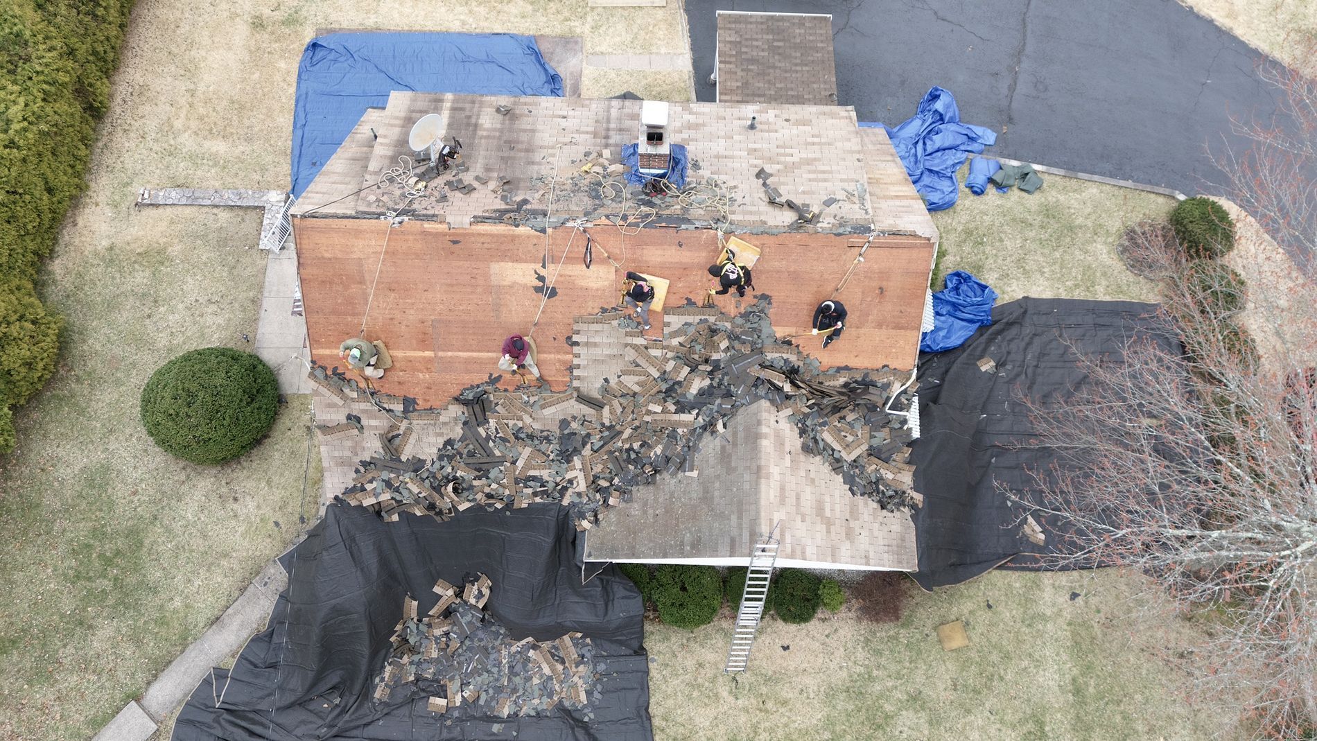 Aerial view of a damaged brick building with a partially collapsed roof and debris around it.