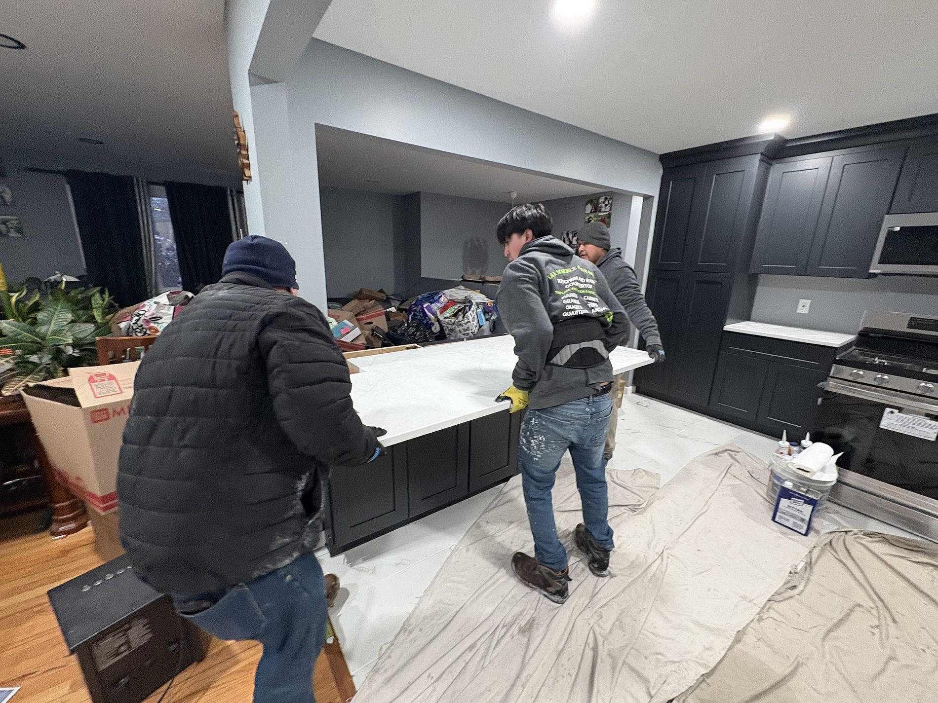Two people moving a white countertop in a modern kitchen during a remodel