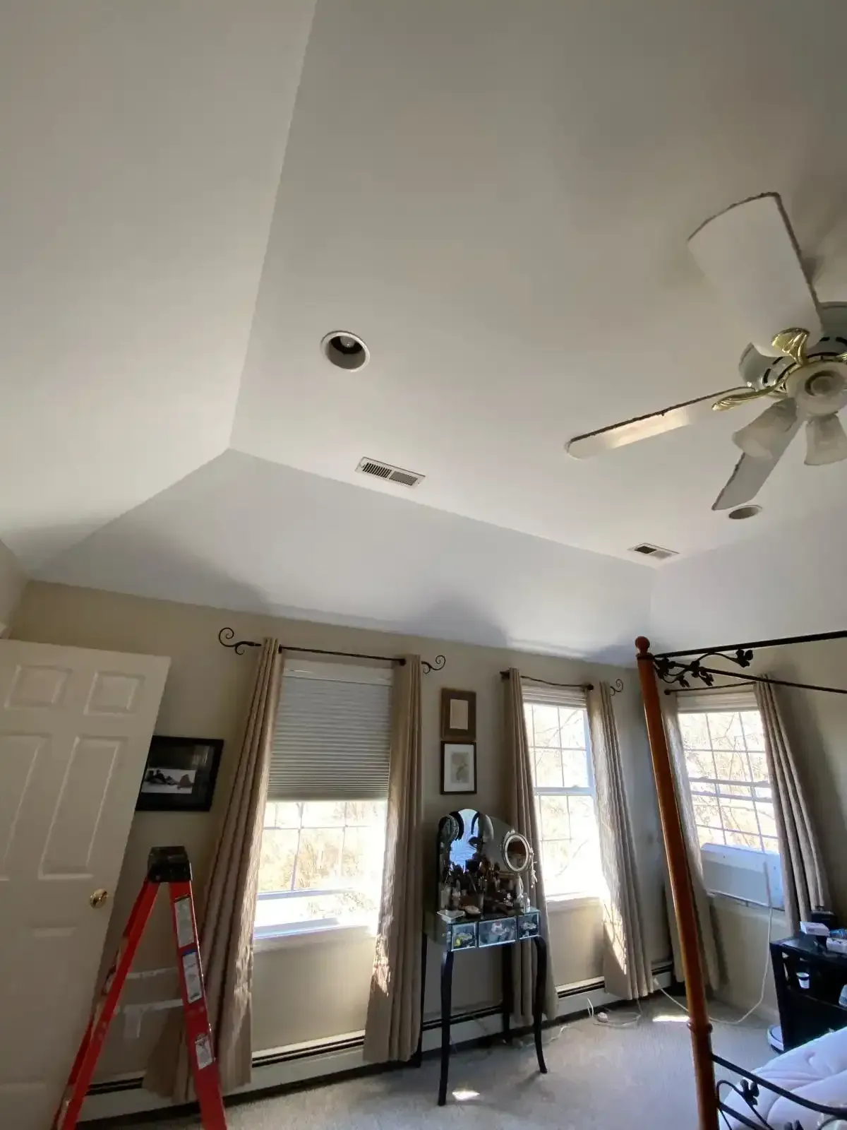 Living room with vaulted ceiling, ceiling fan, windows, ladder, and a tall standing mirror