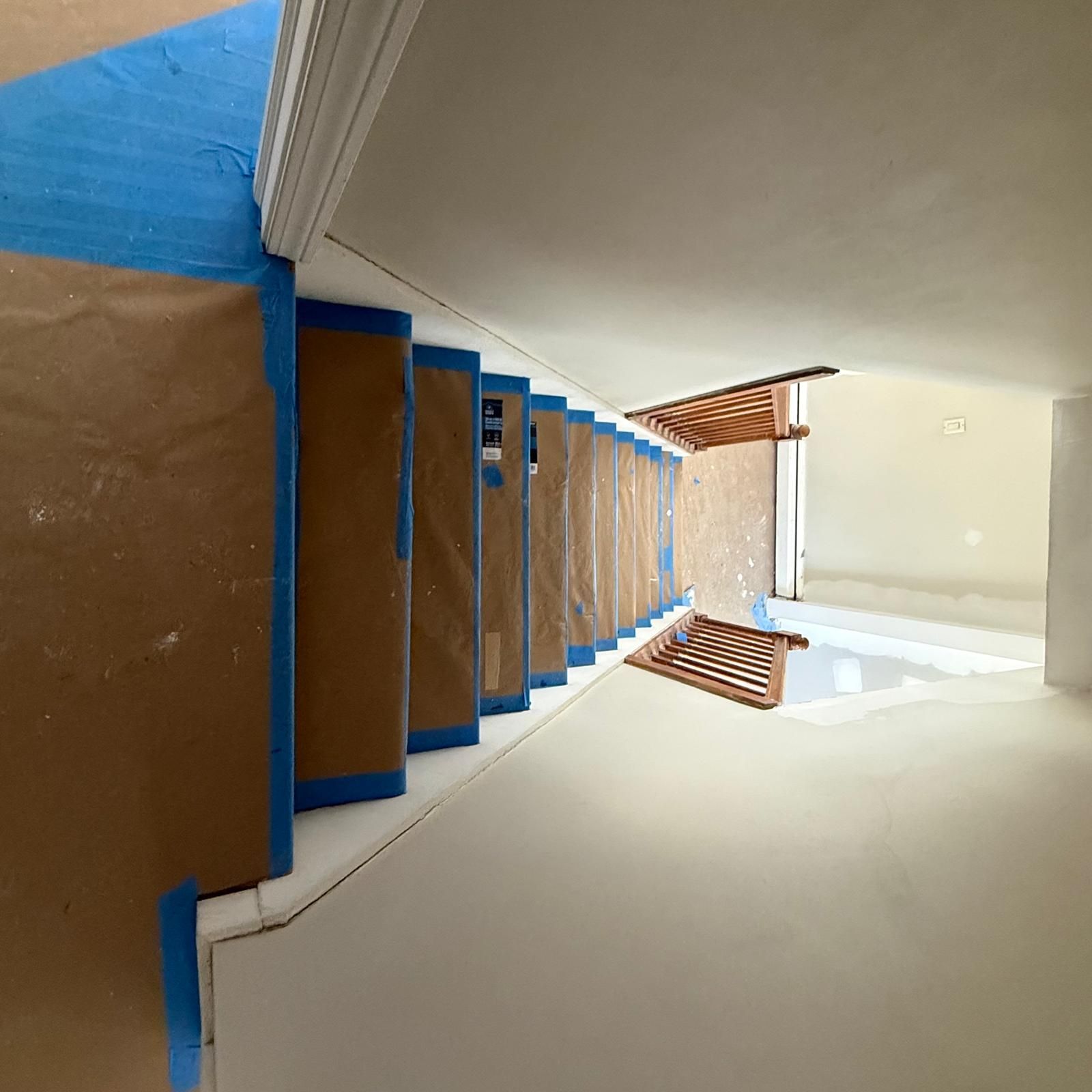 Indoor stairwell with beige walls and blue trim, viewed from below looking up