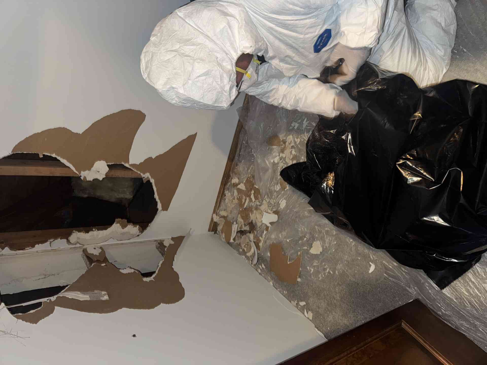Broken cardboard box with torn paper and plastic bags scattered on the floor