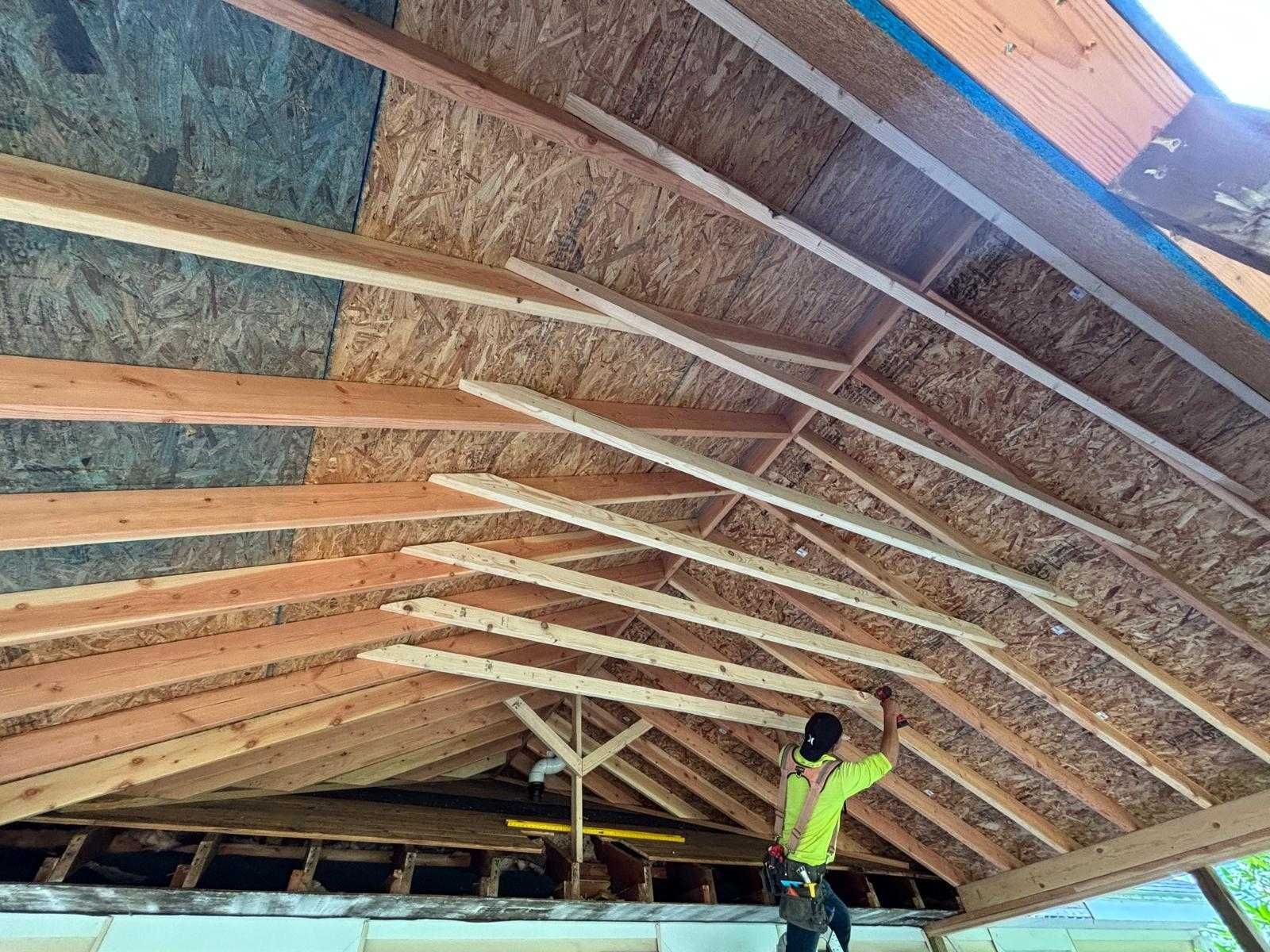 Worker installing insulation under a sloped roof in an unfinished attic