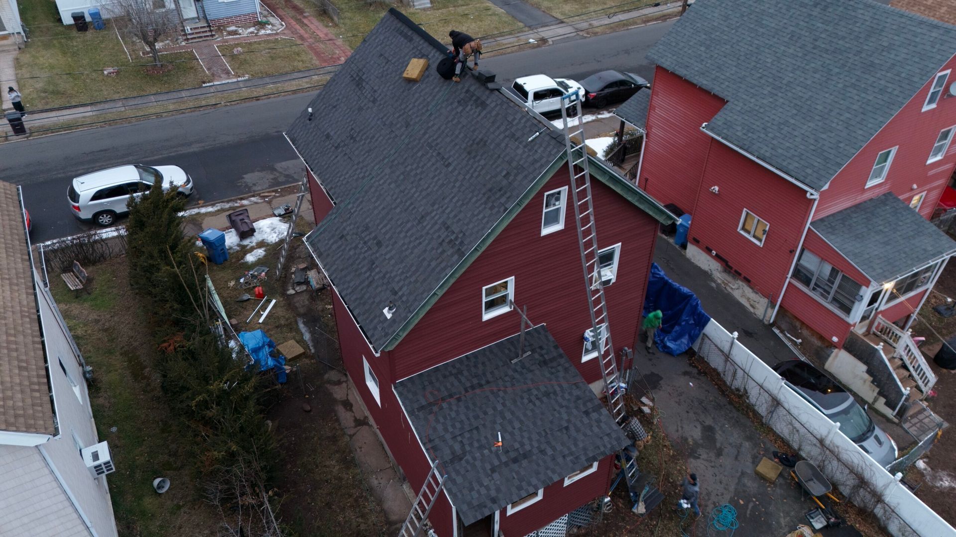 Aerial view of red houses with gray roofs beside a street and parked cars