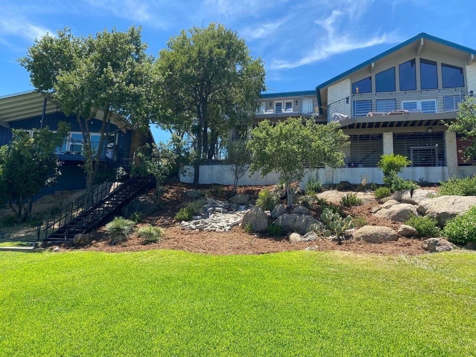 Blue house with large windows on a sunny day, with green grass in the foreground.