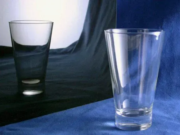 Two clear glass tumblers on a surface with a split blue and black background.