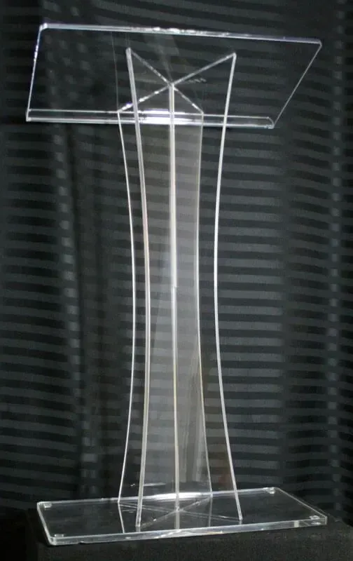 A clear, modern acrylic podium featuring a curved, four-legged pedestal base on a rectangular platform.