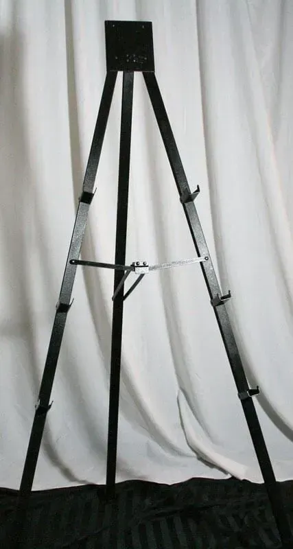 A black metal display easel stands against a white draped background.