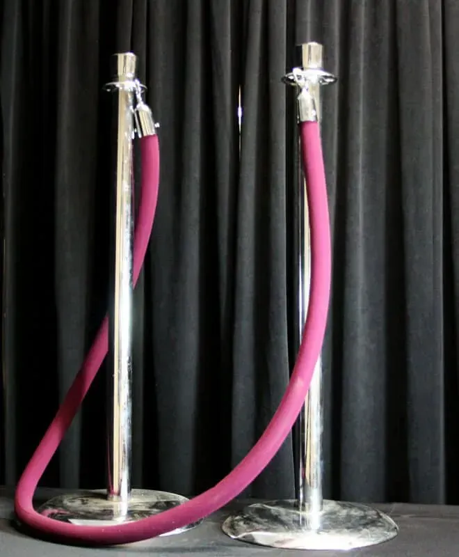 Two chrome stanchions with a pink velvet rope in front of black curtains.