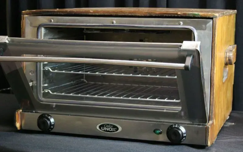 Small countertop toaster oven with a glass door, silver front, and wooden side panels