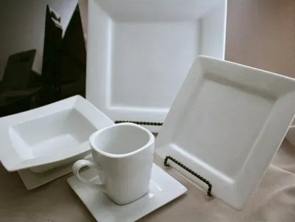 White square ceramic dishware set including a bowl, a cup on a saucer, and two square plates.