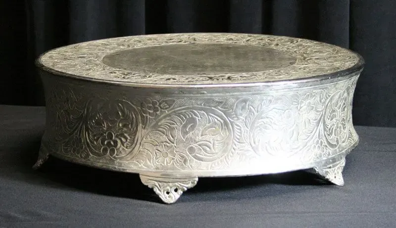 Ornate silver bowl with engraved patterns and short feet on a dark background