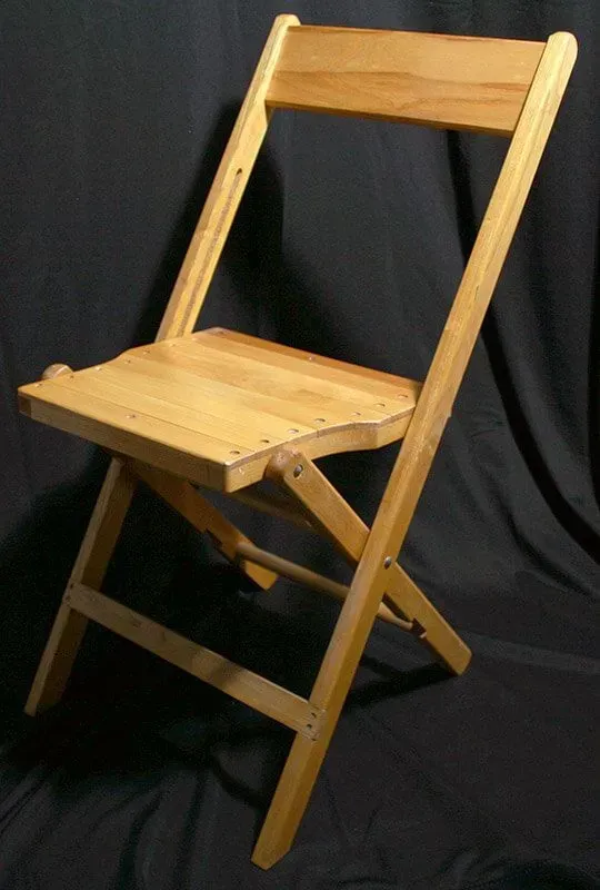 A light-wood folding chair against a black background.