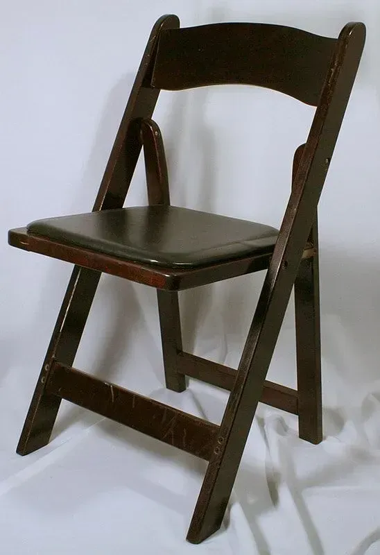 A dark brown wooden folding chair with a black padded seat, set against a plain, light background.